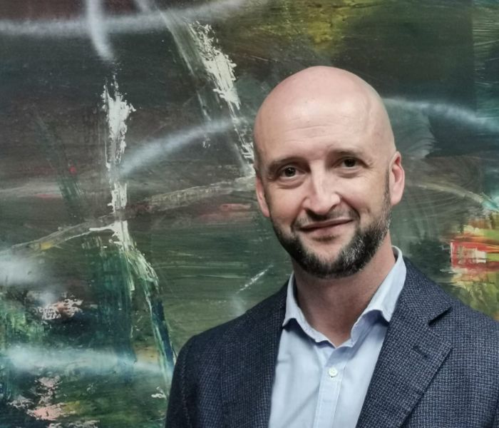 Imagen de Paco Ruiz Molina, mirando a cámara sonriente vestido con camisa azul y chaqueta de traje