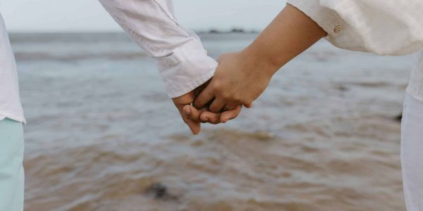 Dos manos agarradas sobre un fondo de playa