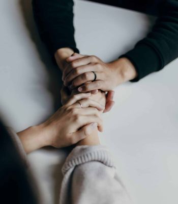 Un par de manos que agarran otro par de manos sobre una mesa blanca